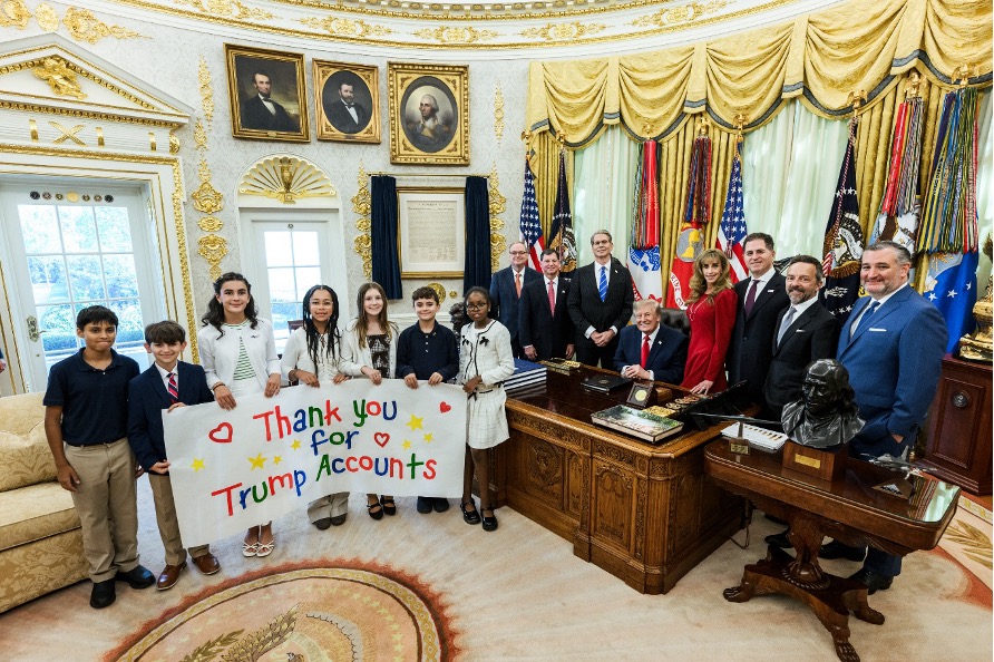 Niños con cartel de agradecimiento por las cuentas de inversión infantiles junto al presidente de Estados Unidos y funcionarios en la Oficina Oval, octubre de 2026