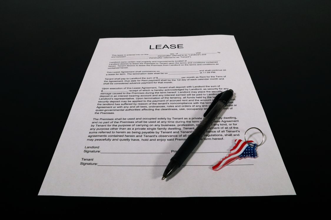 Contrato de alquiler, bolígrafo y llaves sobre una mesa.